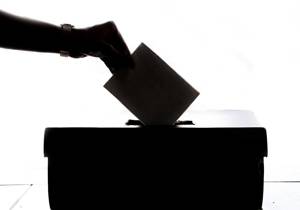 Hand die een stembiljet in een stembus stopt.