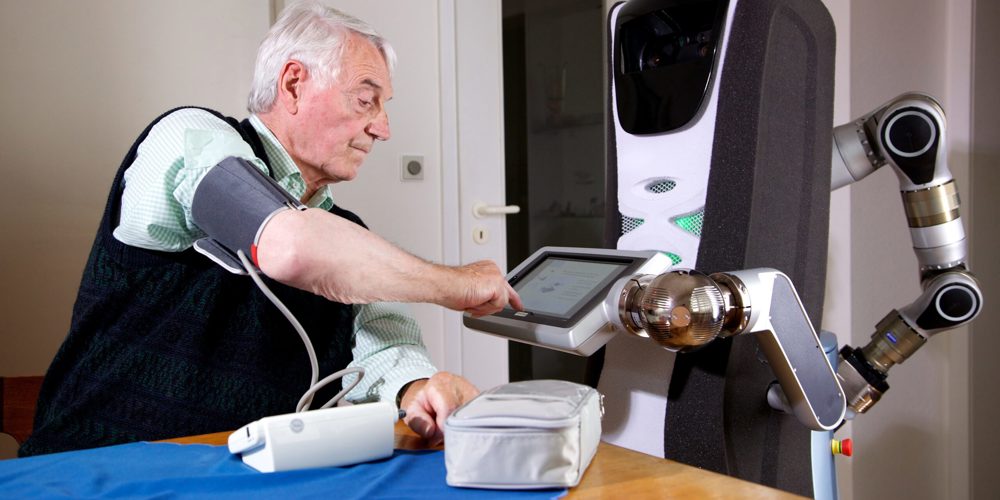 Een oudere man meet zijn bloeddruk met behulp van een zorgrobot met een touchscreen.