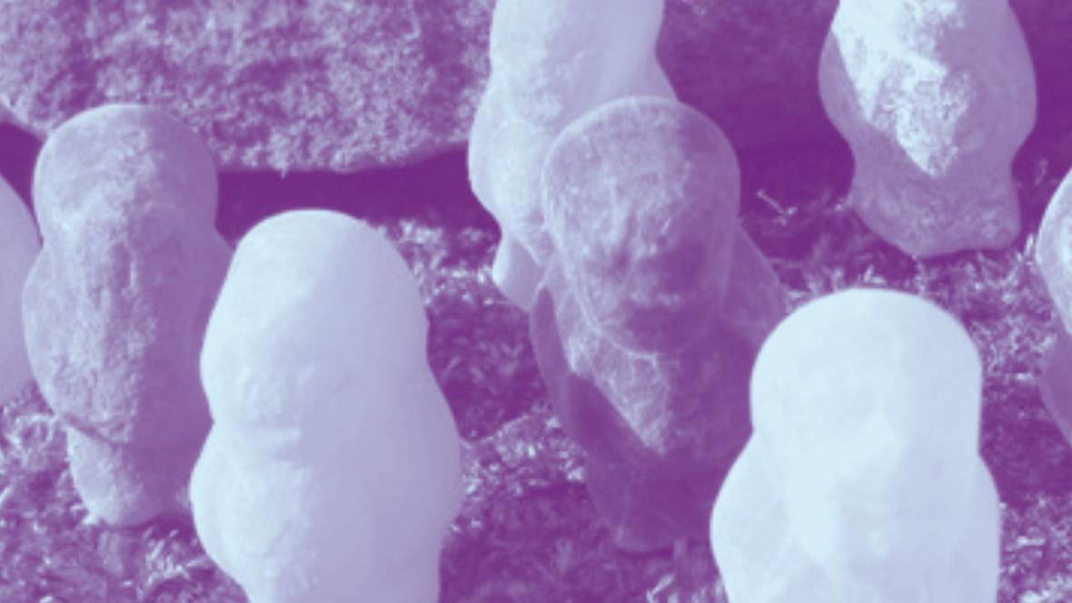 Kleine stenen figurenop de grond, met een grote steen op de achtergrond.